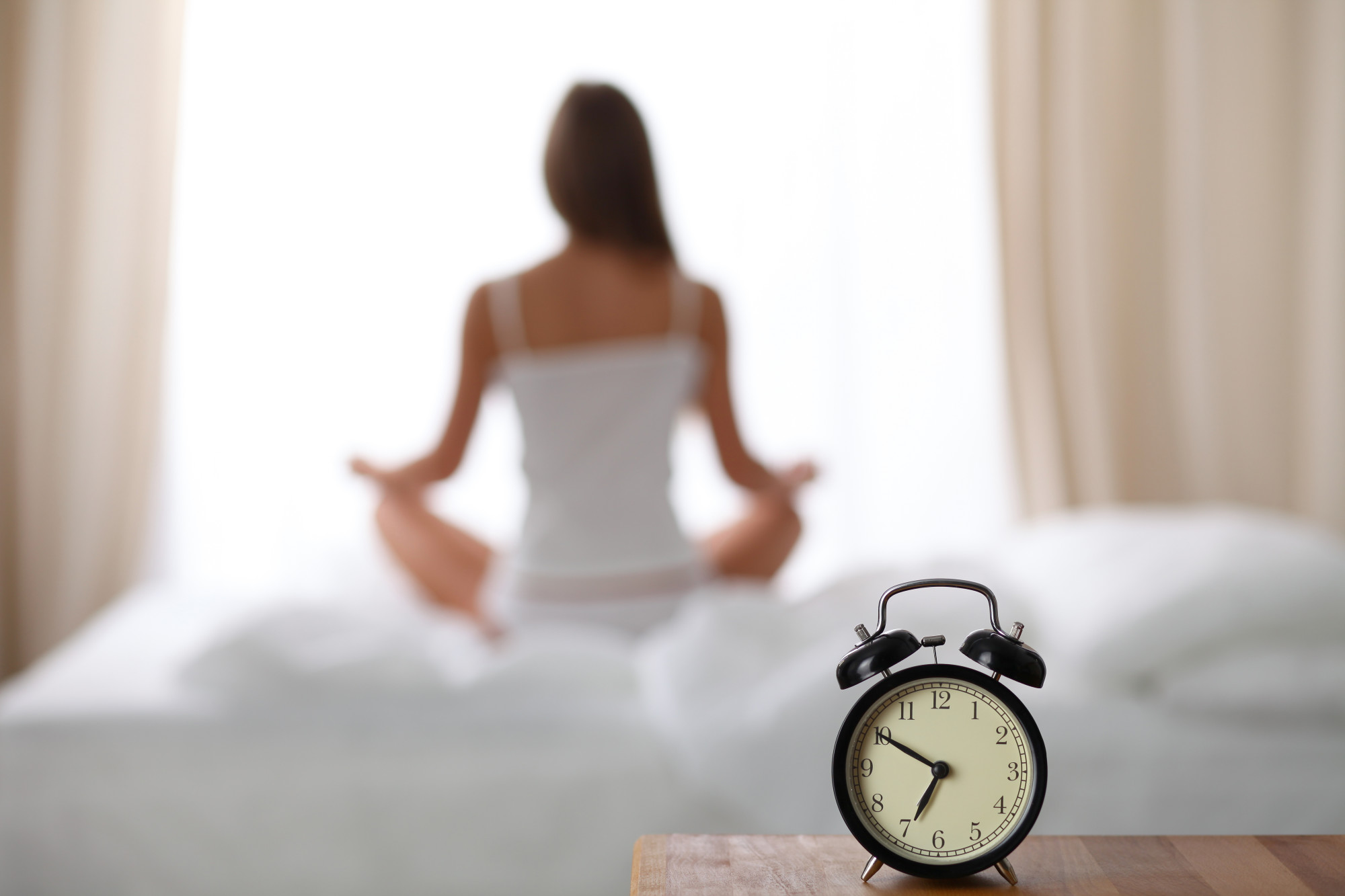 Alarm Clock Standing On Bedside Table Has Already Rung Early Morning To Wake Up Woman Do Yoga In Bed In Background Early Awakening Healthy Lifestyle Contemplation Concept